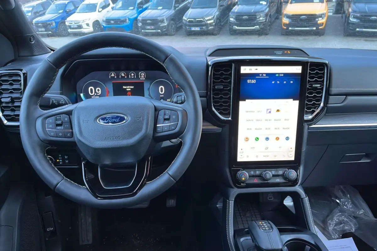 Vue intérieure centrée sur le volant cuir multifonctions et l’écran tactile vertical du Ford Ranger blanc glacier 2025.