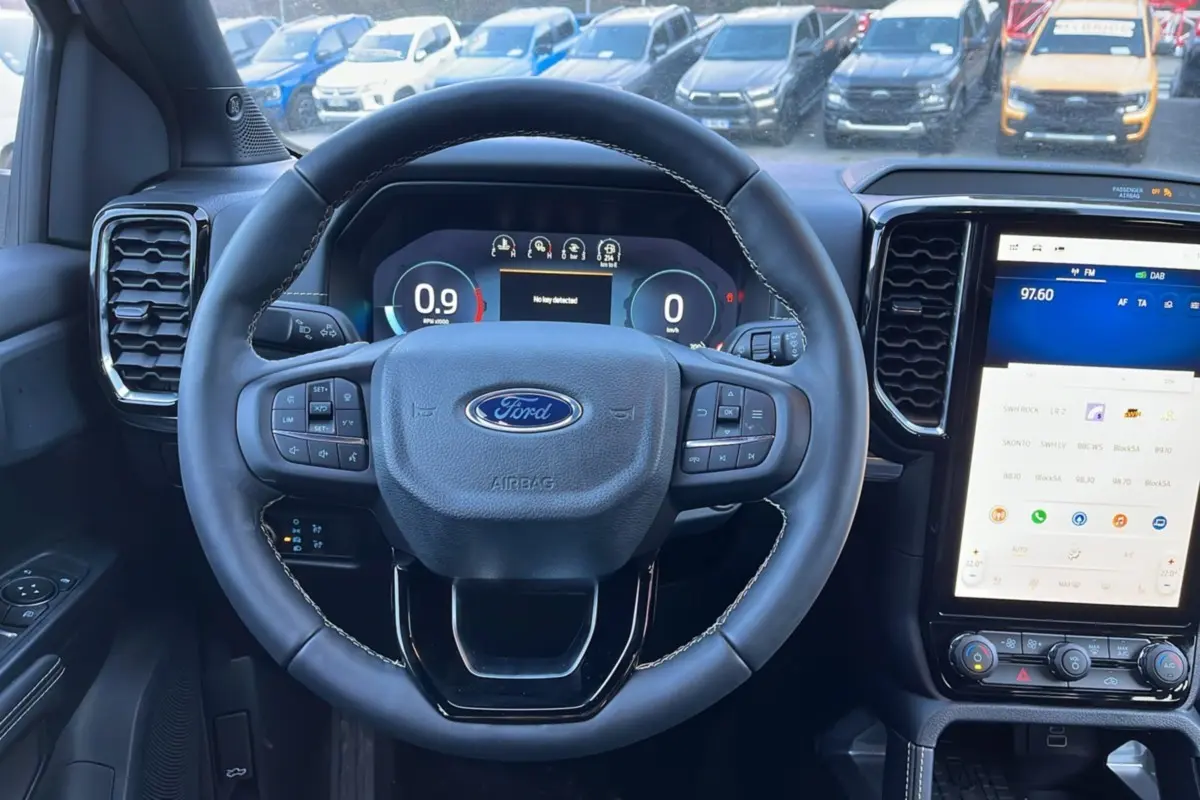 Vue intérieure centrée sur le volant cuir multifonctions du Ford Ranger 2025, avec écran tactile vertical et tableau de bord numérique.