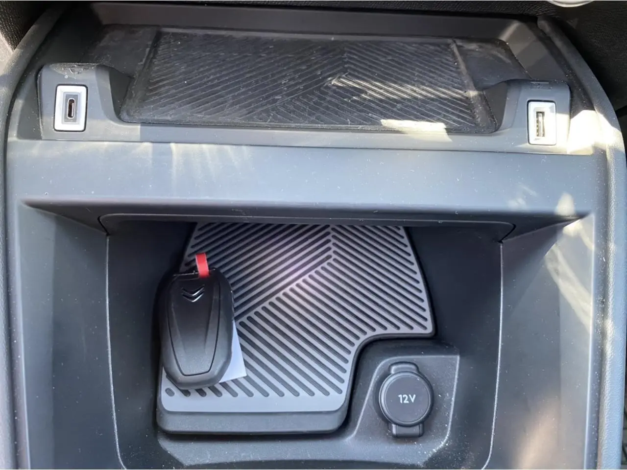 Gros plan sur la console centrale d’une Citroën C4 gris foncé 2021, avec clé et prise 12V visibles.