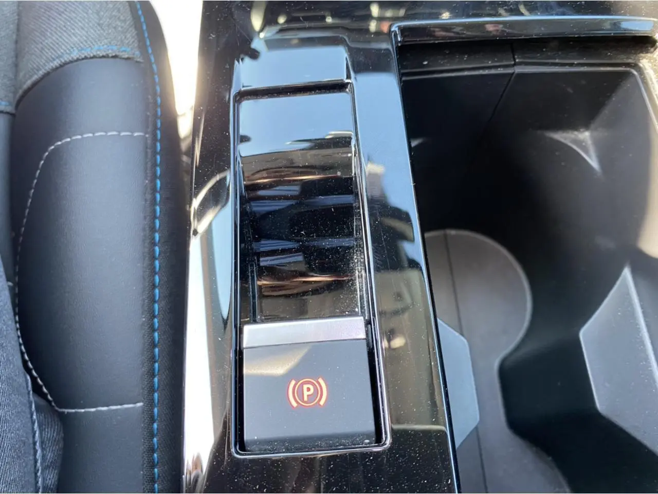 Gros plan sur la console centrale du Citroën C4 gris foncé 2021, mettant en valeur le frein à main électronique.