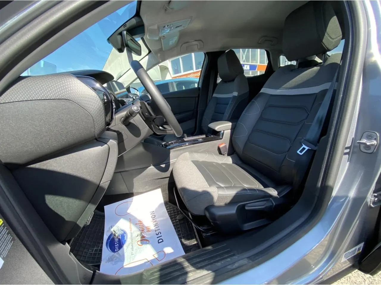 Intérieur avant droit de la Citroën C4 gris foncé 2021, sièges bi-matière avec console centrale et volant visible.
