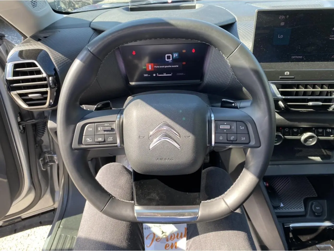 Vue rapprochée du volant de la Citroën C4 2021 gris foncé, avec commandes intégrées et tableau de bord digital.