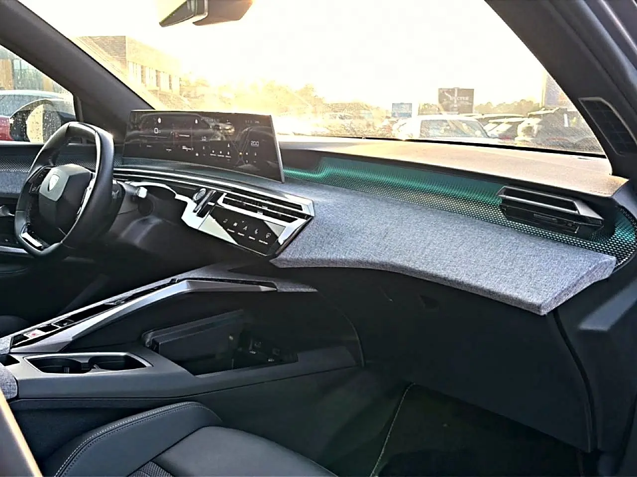 Vue intérieure côté passager du tableau de bord gris et noir du Peugeot 3008 1.2 hybrid 145 GT avec écran tactile et volant cuir.