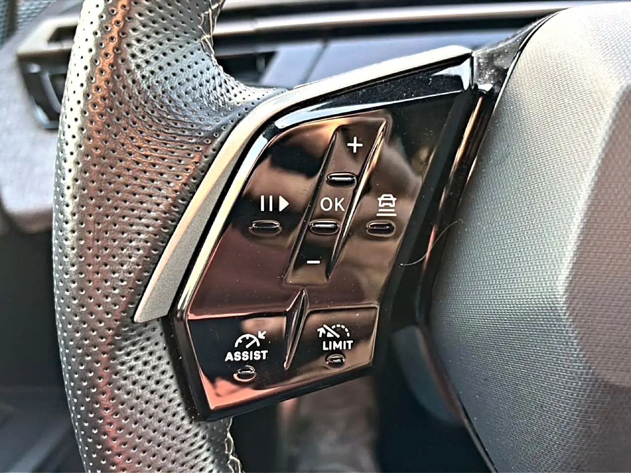 Gros plan sur les commandes noires multifonctions au volant cuir perforé côté gauche du Peugeot 3008 gris 2025.
