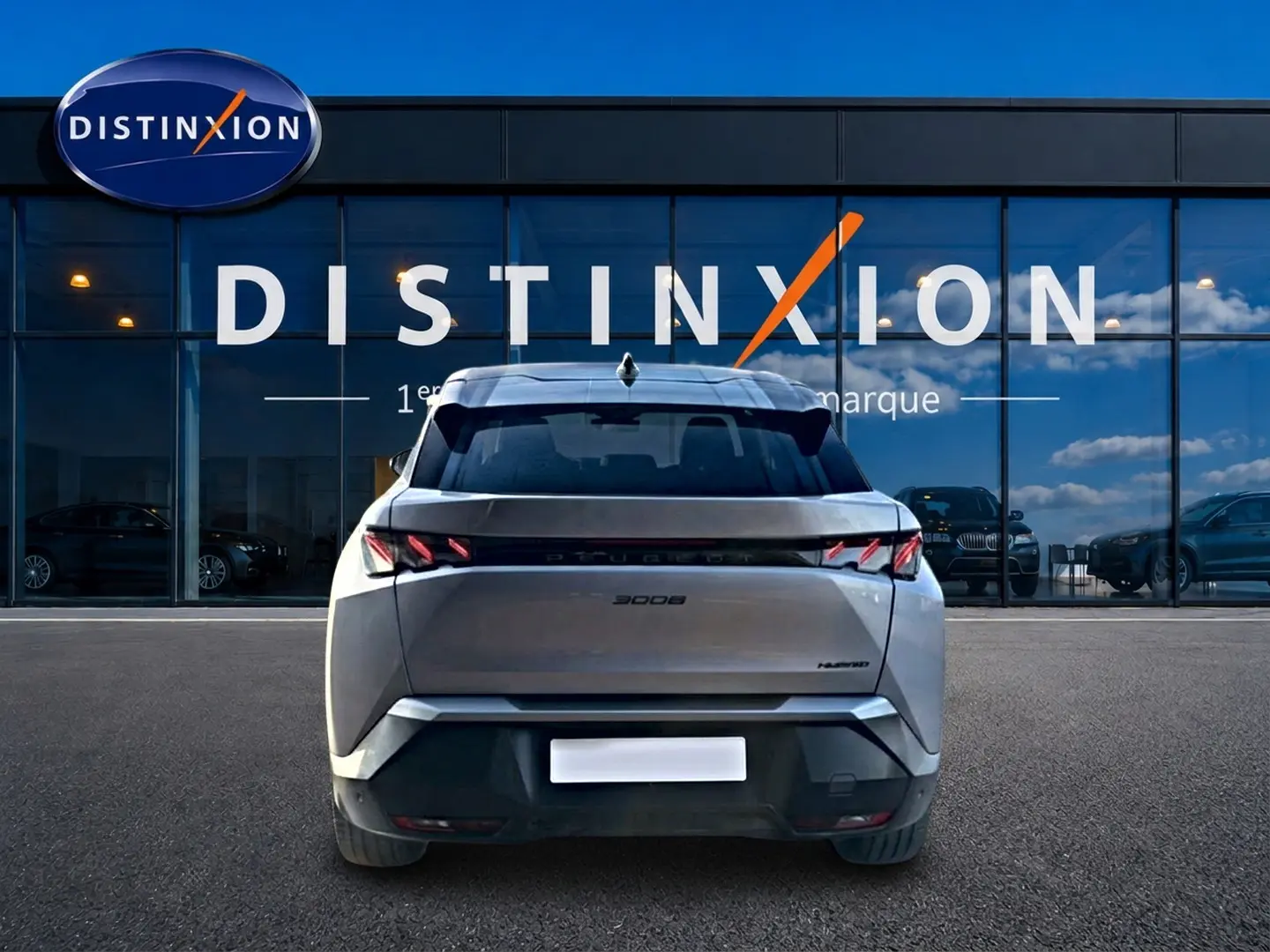 Vue arrière d'un Peugeot 3008 gris 2025 avec feux LED distinctifs, garé devant une vitrine Distinxion.