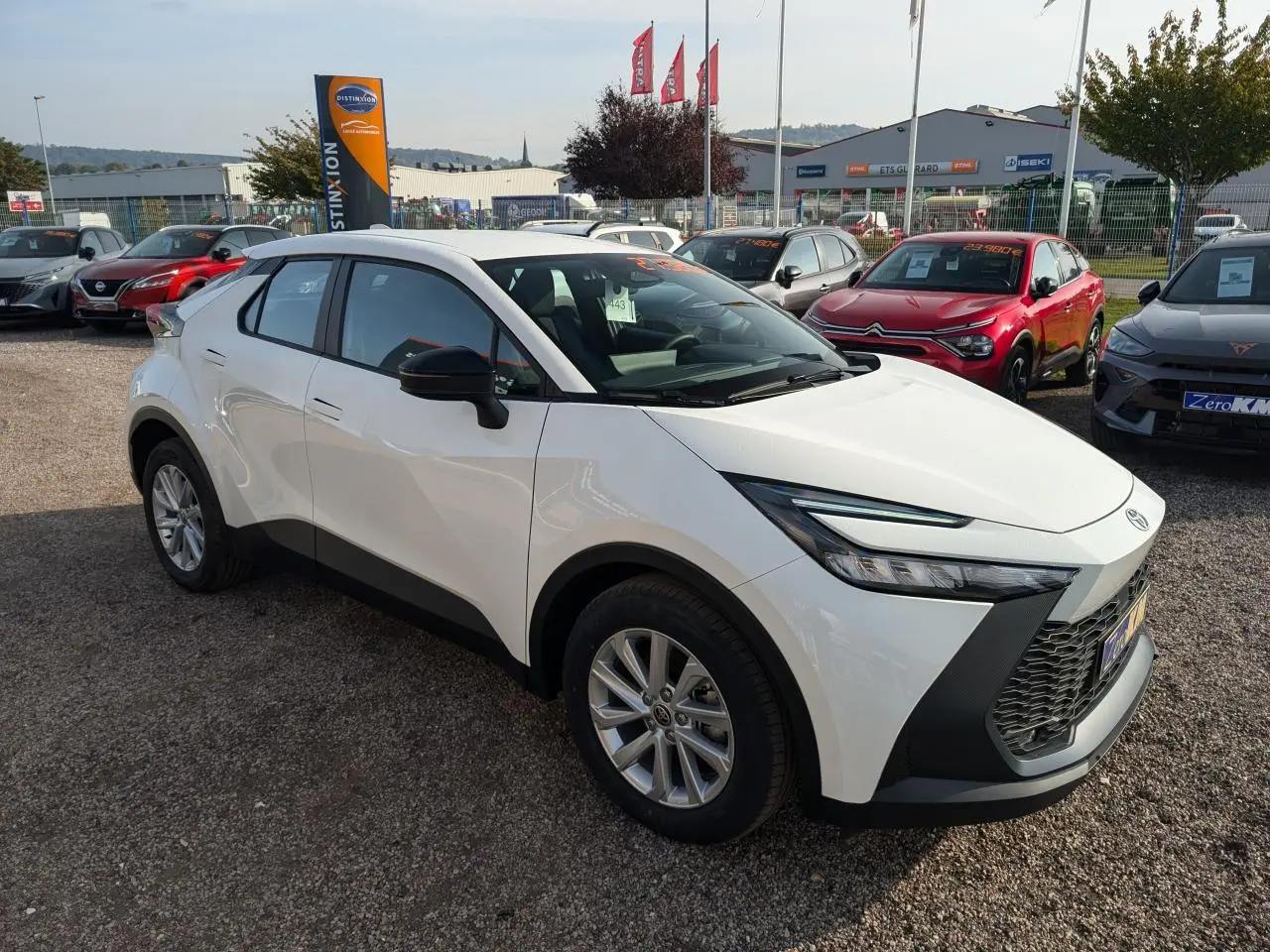 Toyota C-HR blanc vue 3/4 avant droit, avec calandre noire et jantes alliage, stationné en extérieur.