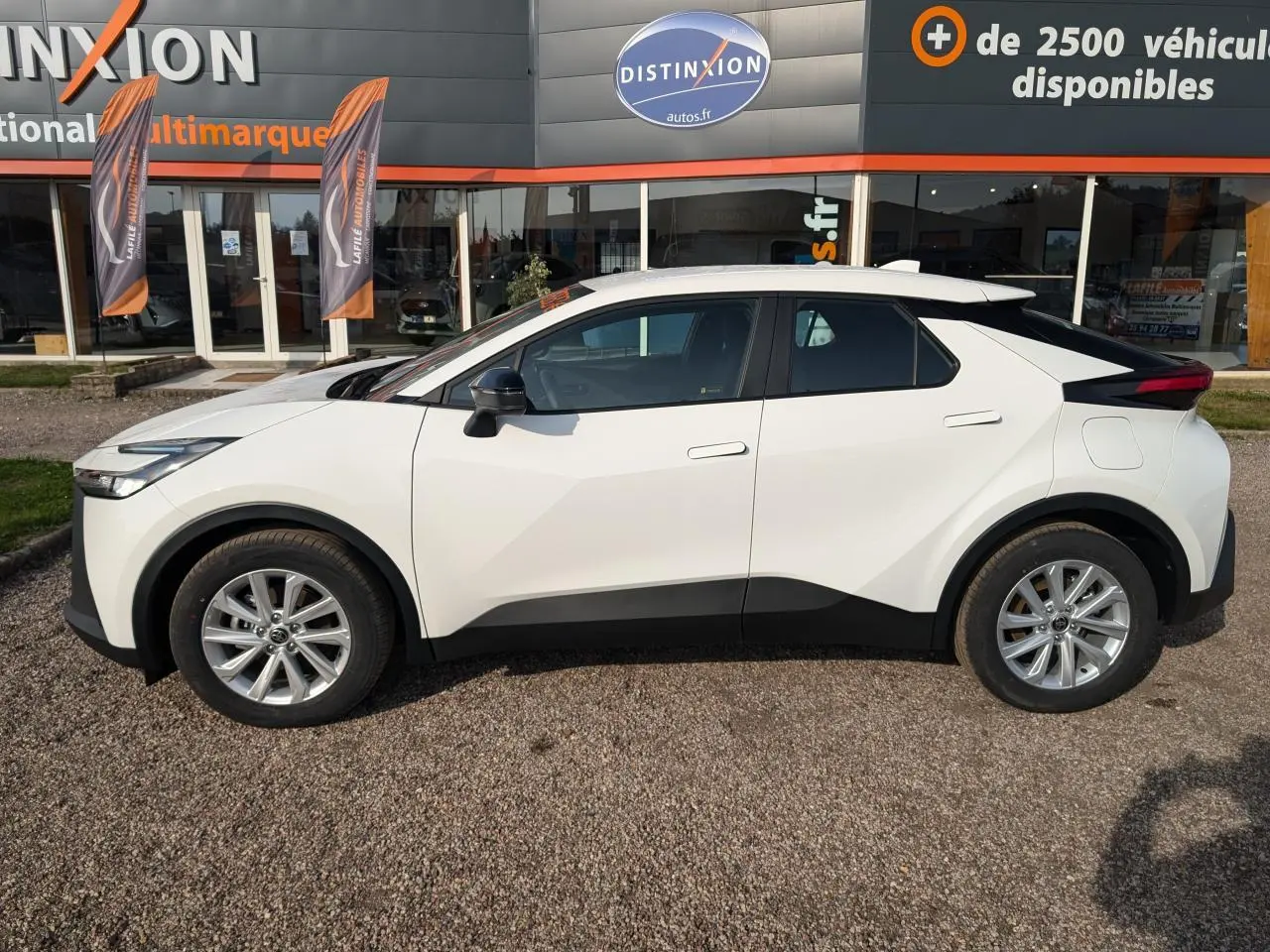 Vue latérale droite du Toyota C-HR 1.8 Hybrid blanc 2024 avec détails noirs contrastants et jantes alliage.