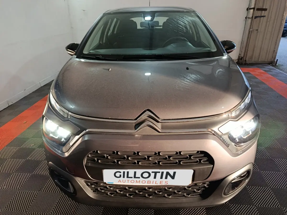 Vue avant d'une Citroën C3 gris foncé 2024 avec phares LED allumés dans un garage fermé.
