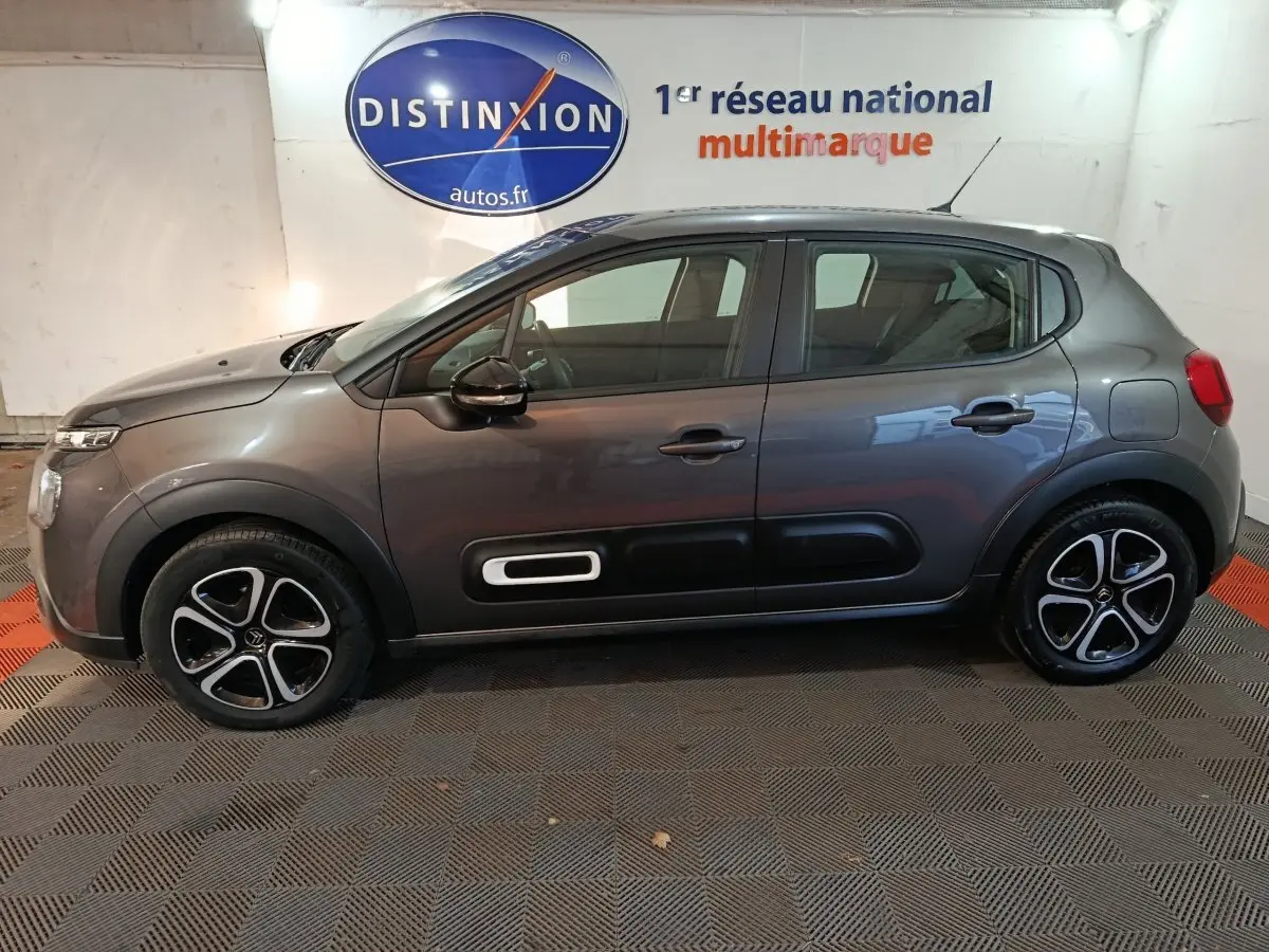 Vue de profil côté gauche d'une Citroën C3 2024 gris foncé avec protections latérales noires et jantes stylisées.
