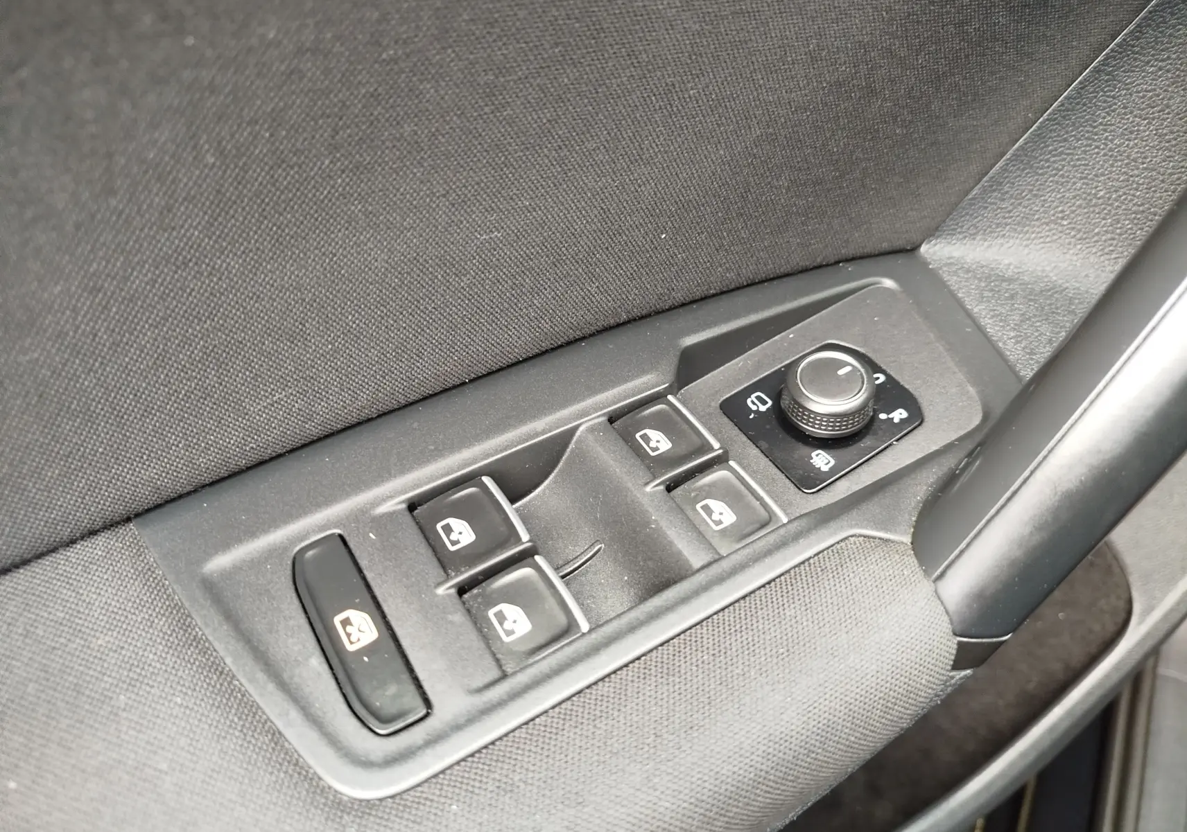 Gros plan sur les commandes de lève-vitres et réglage des rétroviseurs côté conducteur d’un Volkswagen Tiguan noir 2019.