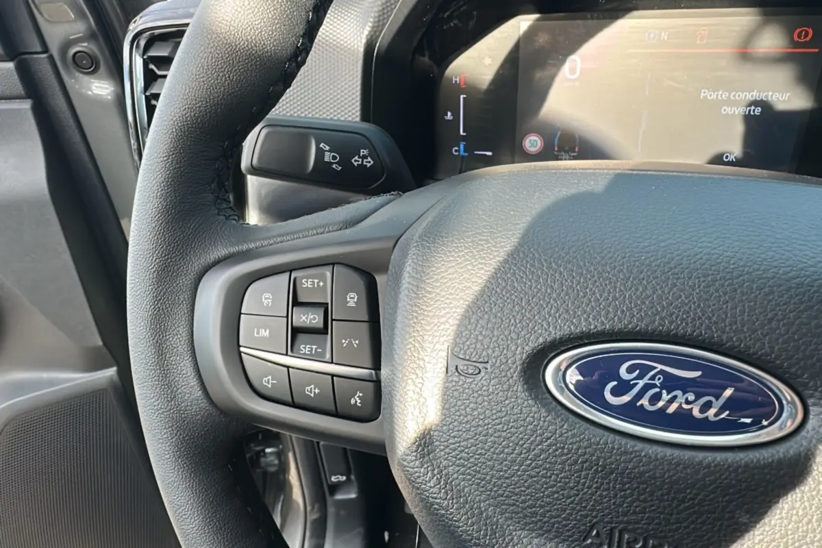 Gros plan sur le volant en cuir noir du Ford Ranger 2025 avec commandes multifonctions et tableau de bord digital.