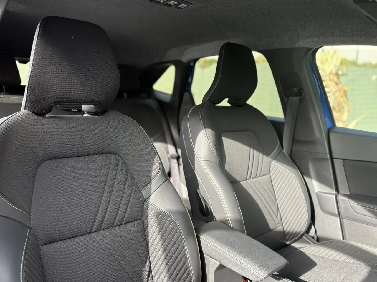 Vue intérieure des sièges avant en tissu gris avec surpiqûres contrastantes dans une Renault Symbioz bleu Iron.