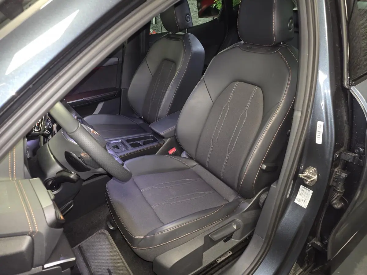 Vue intérieure côté conducteur du CUPRA Formentor gris 2025, sièges sport bimatière noirs avec surpiqûres cuivrées.