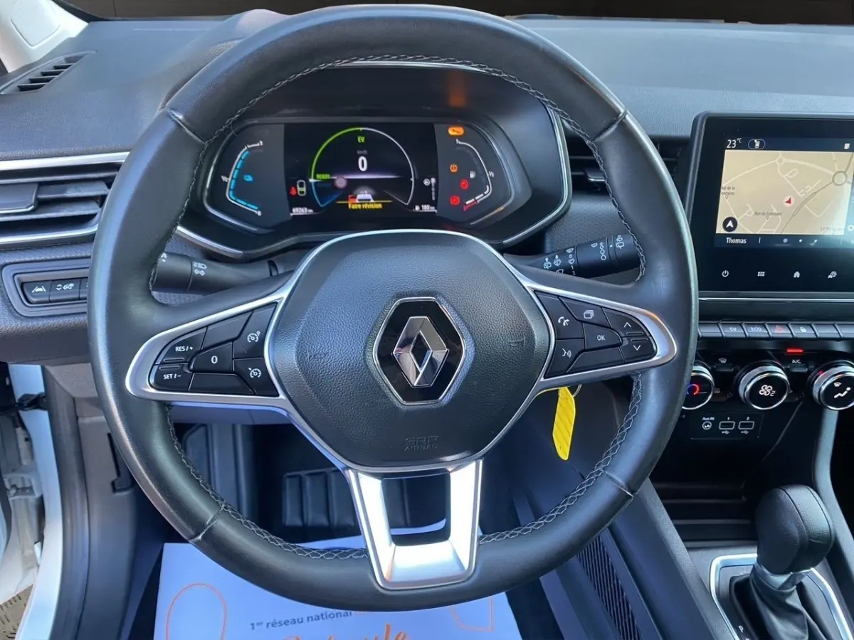 Vue intérieure centrée sur le volant cuir noir de la Renault Clio Business E-TECH 140 avec tableau de bord numérique et écran tactile.