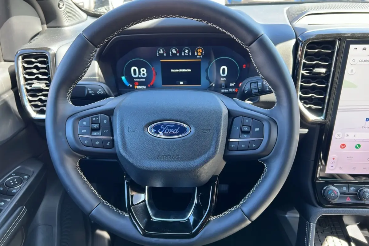Vue rapprochée du volant cuir multifonctions noir avec logo Ford et tableau de bord numérique du Ford Ranger 2025.