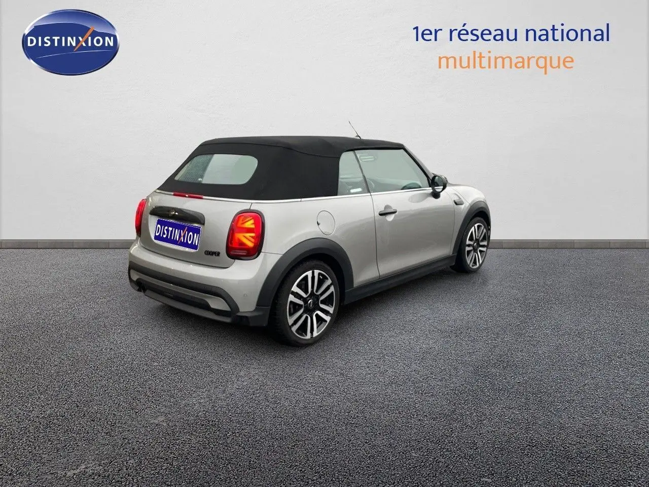Vue 3/4 arrière droite d'une MINI Cabriolet F57 2023 Melting Silver Metal avec capote noire et feux arrière à motif Union Jack.