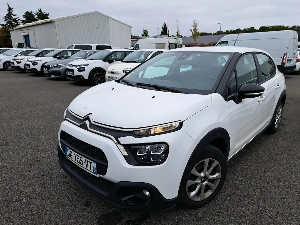 Citroën C3 Société blanche vue en 3/4 avant droit, avec calandre noire et feux LED allumés sur parking.