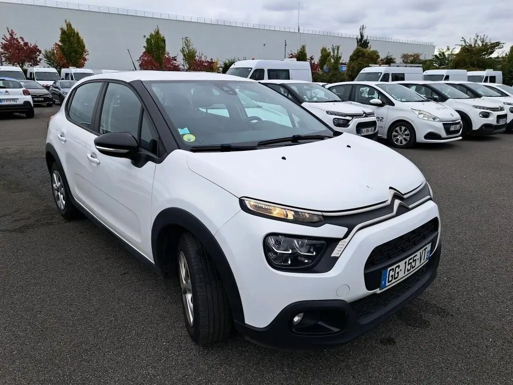 Citroën C3 Société blanche vue en 3/4 avant gauche sur parking avec calandre noire et feux allumés.