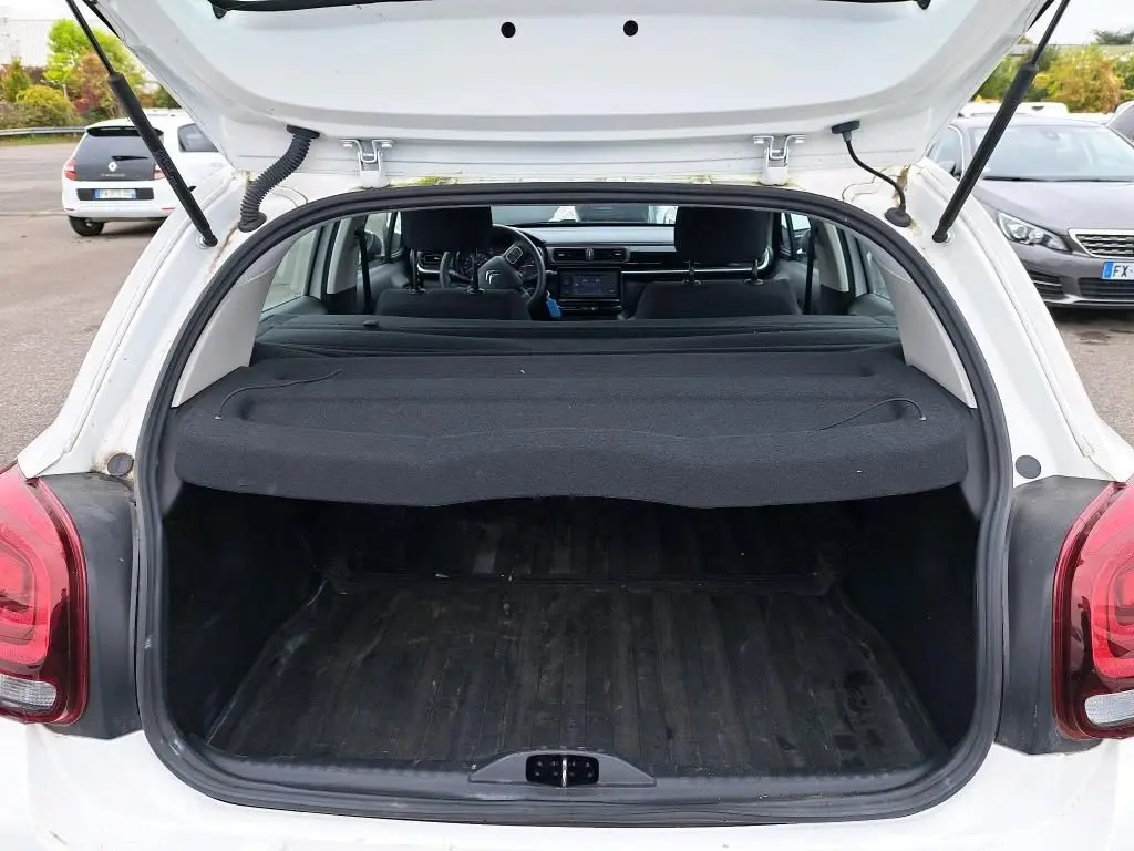 Coffre ouvert vu de l'arrière d'une Citroën C3 Société blanche, avec cache-bagages et intérieur noir visible.