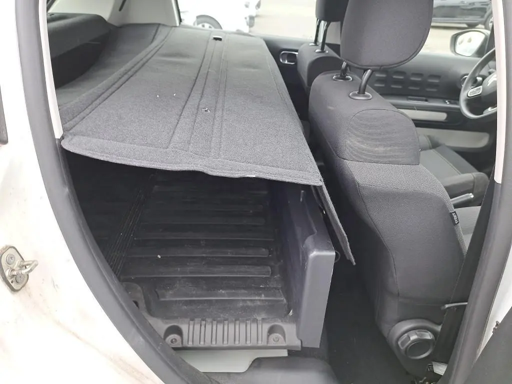 Vue intérieure côté gauche du Citroën C3 Société blanc 2022, montrant la banquette rabattue et le coffre de chargement.