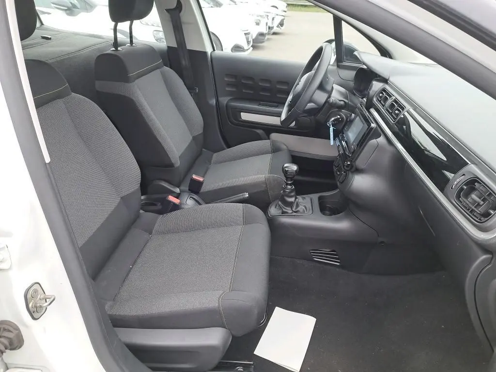 Intérieur de la Citroën C3 Société blanc, vue côté conducteur montrant sièges tissu gris et tableau de bord moderne.