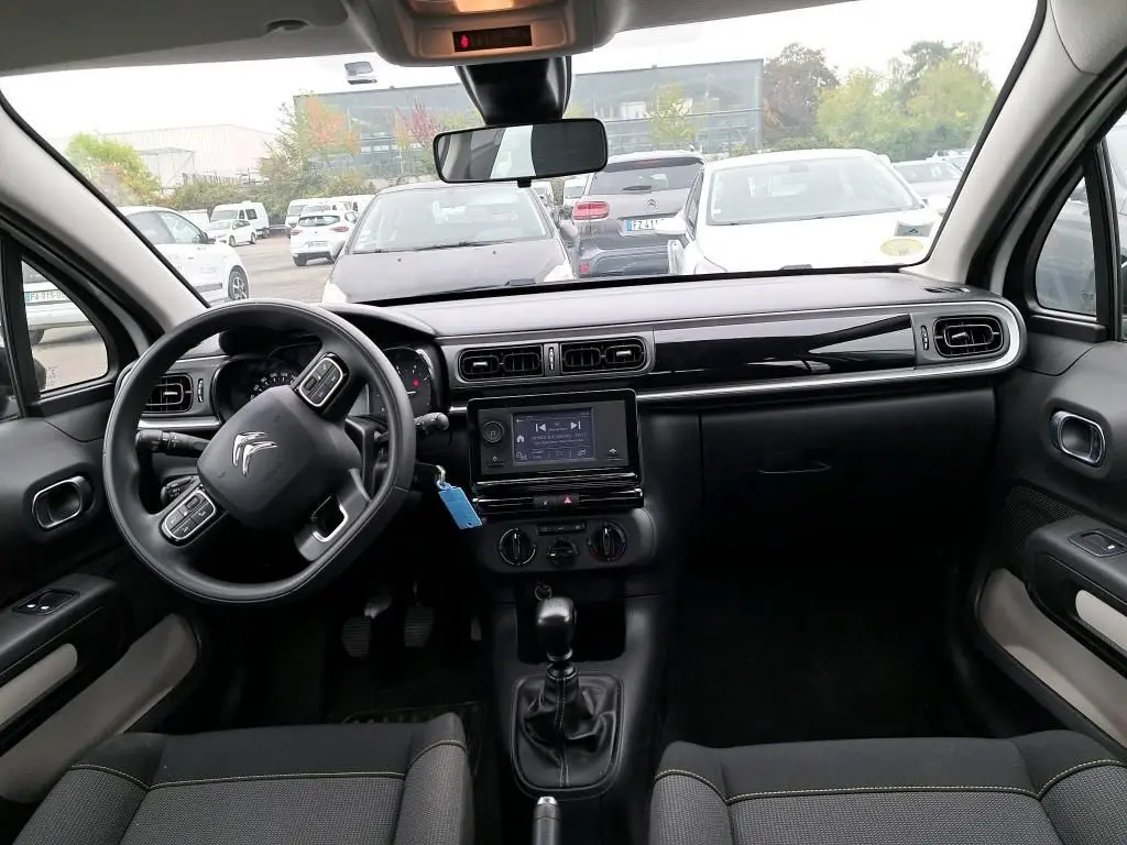 Vue intérieure avant du Citroën C3 Société blanc 2022, tableau de bord noir avec écran tactile et volant multifonction.