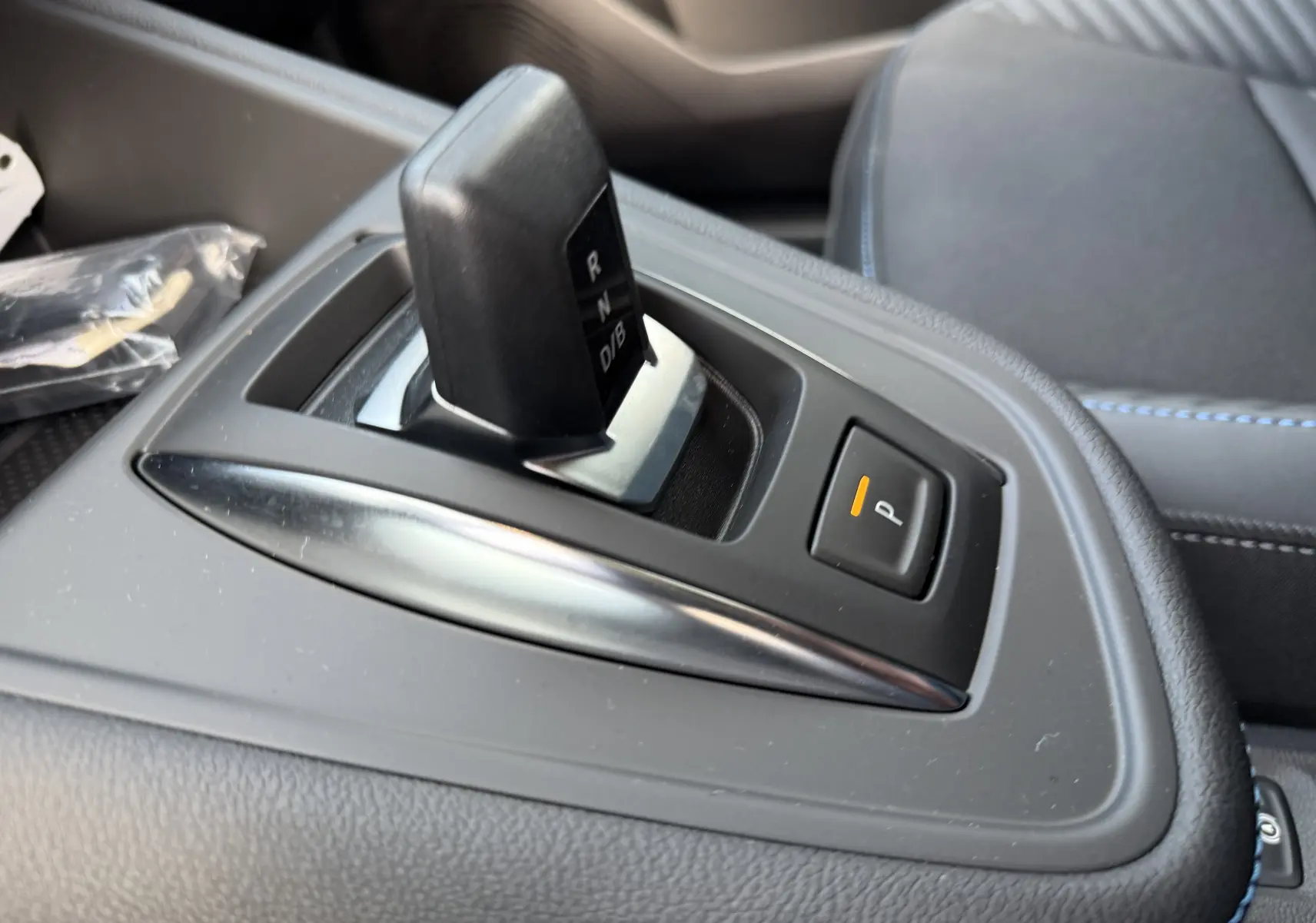 Gros plan sur le levier de vitesse automatique noir et bouton de parking orange dans l’habitacle gris du Renault Symbioz 2025.