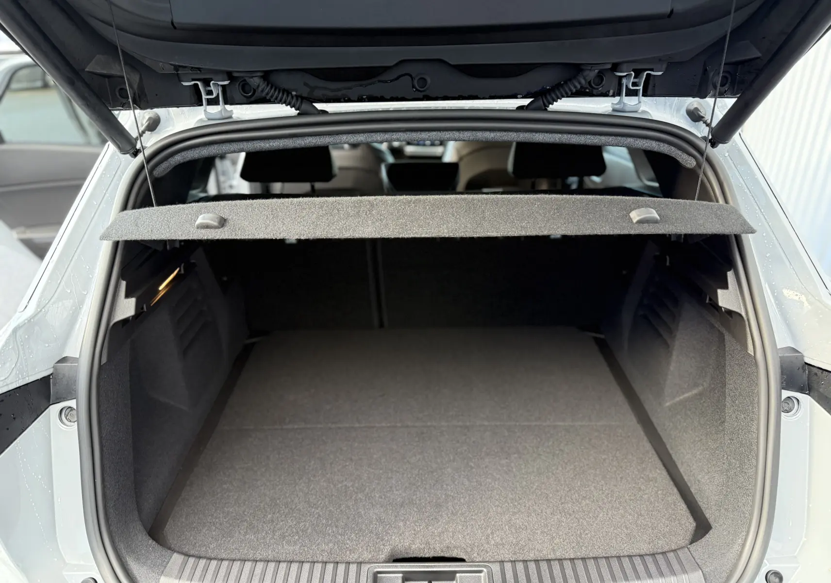 Coffre ouvert vu de l'arrière d'une Renault Symbioz gris rafale, montrant un espace de chargement spacieux et propre.