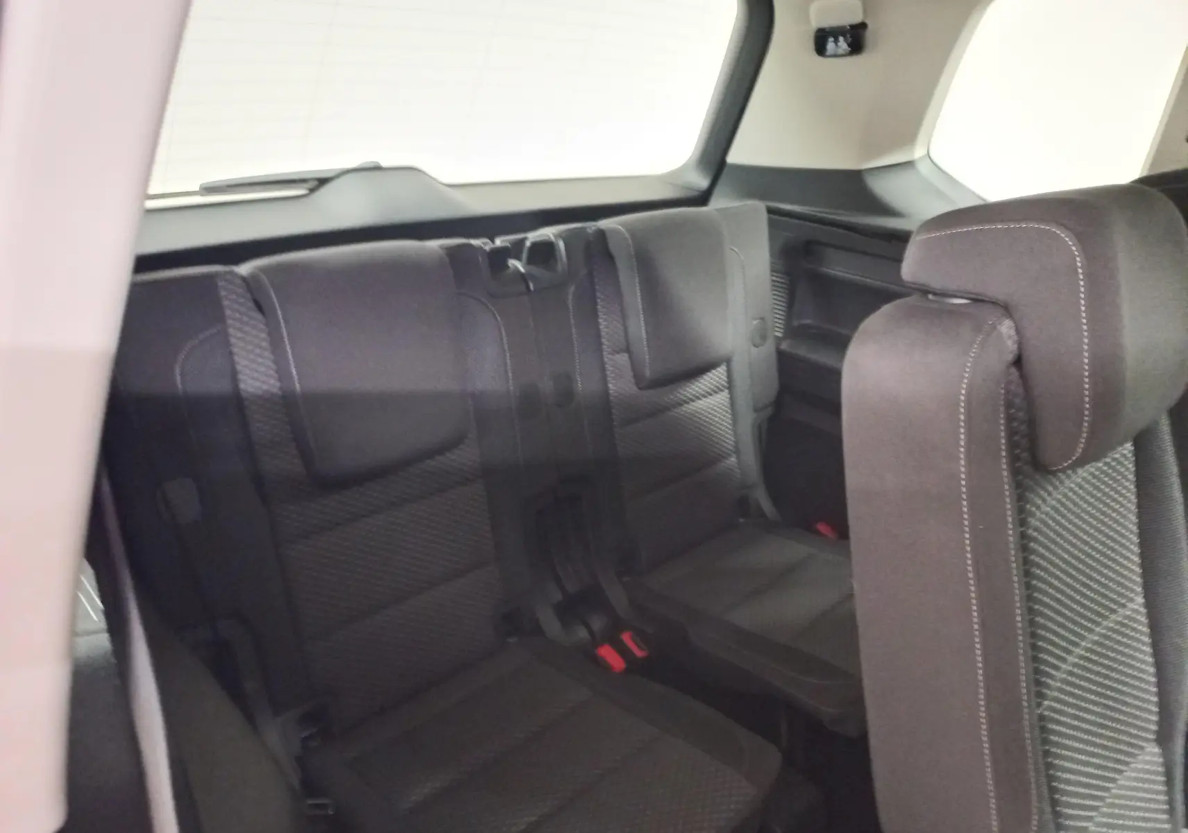 Vue intérieure sur la troisième rangée de sièges en tissu gris du Volkswagen Touran 2025, version 7 places.