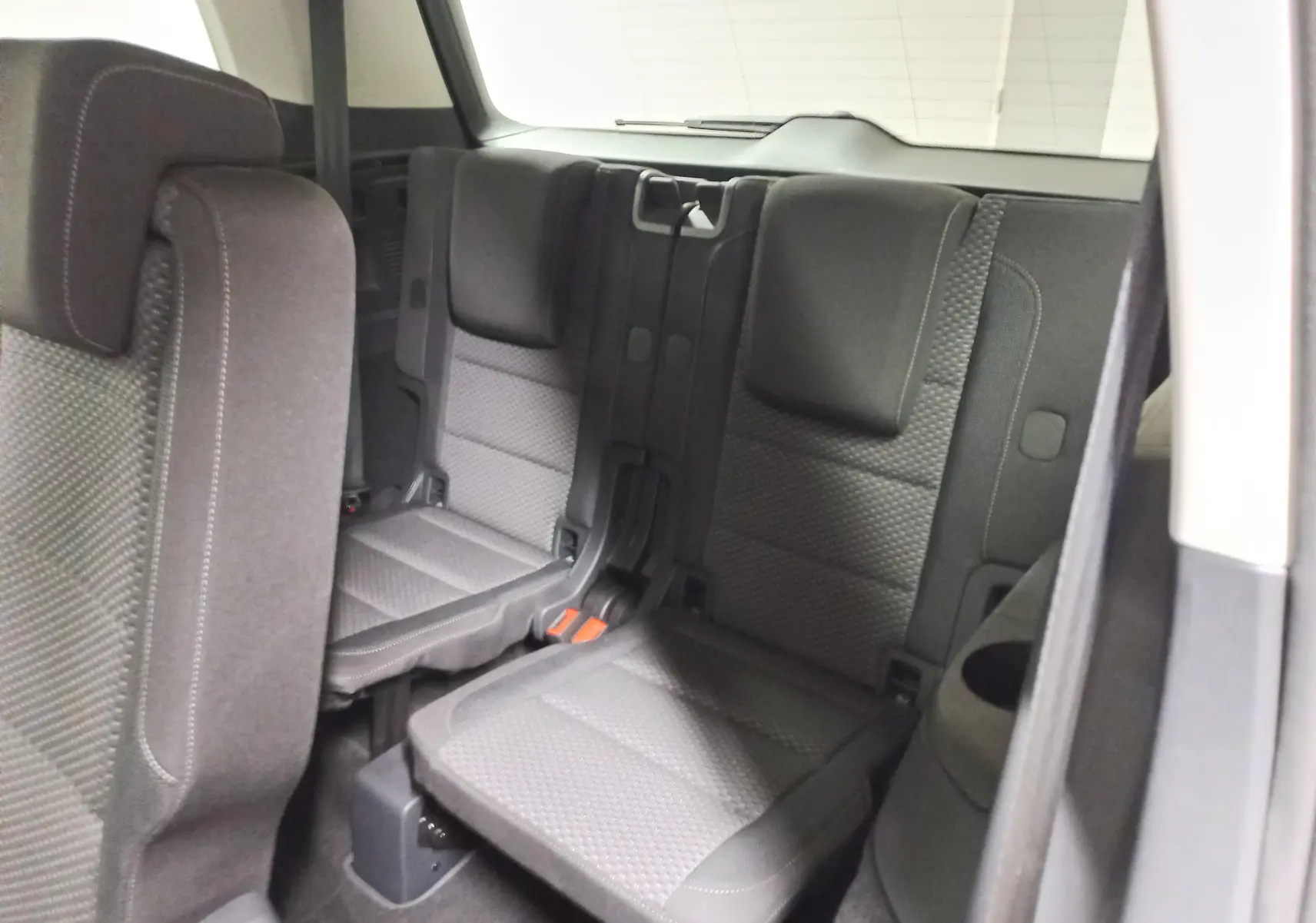 Vue intérieure sur la troisième rangée de sièges en tissu gris foncé du Volkswagen Touran 2025, version 7 places.