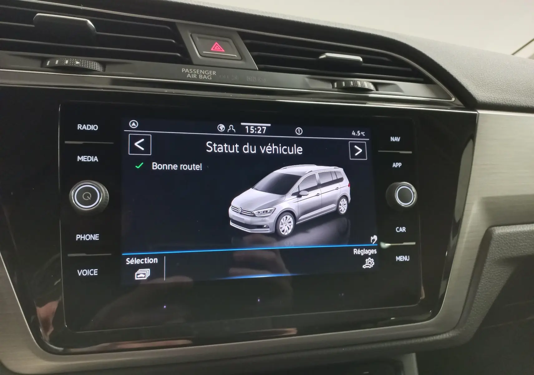 Écran tactile du tableau de bord affichant le statut du Volkswagen Touran gris dauphin en vue 3/4 avant.