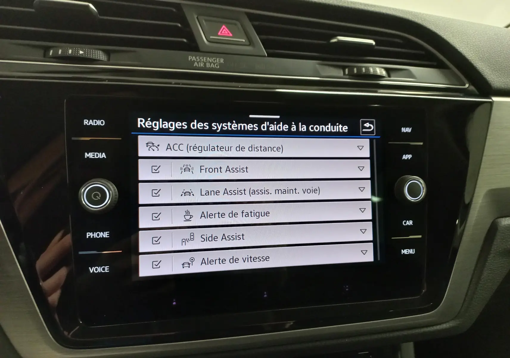Écran tactile central du Volkswagen Touran 2025 affichant les réglages des aides à la conduite, intérieur noir.