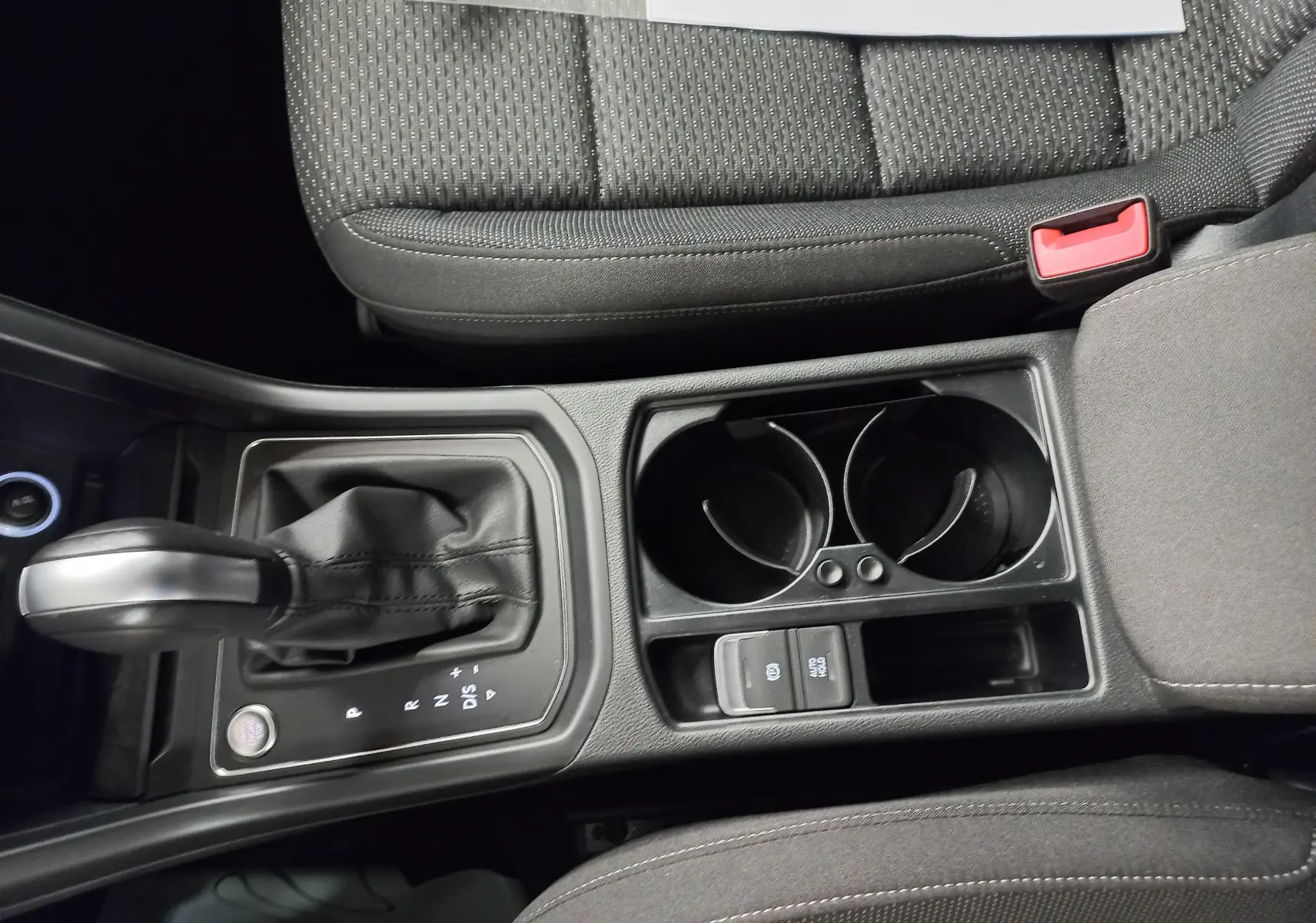 Vue rapprochée de la console centrale du Volkswagen Touran 2025, avec levier de vitesse automatique et porte-gobelets noirs.
