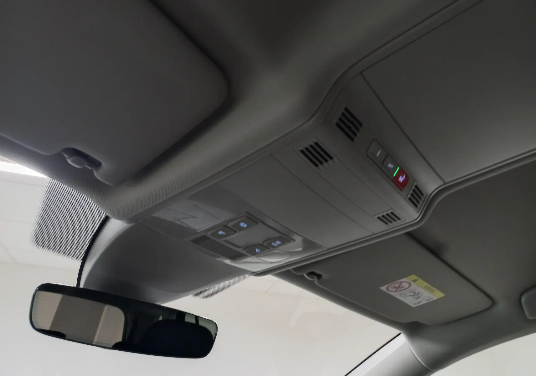 Vue intérieure du plafond avec commandes d'éclairage et rétroviseur dans un Volkswagen Touran gris Dauphin 2025.