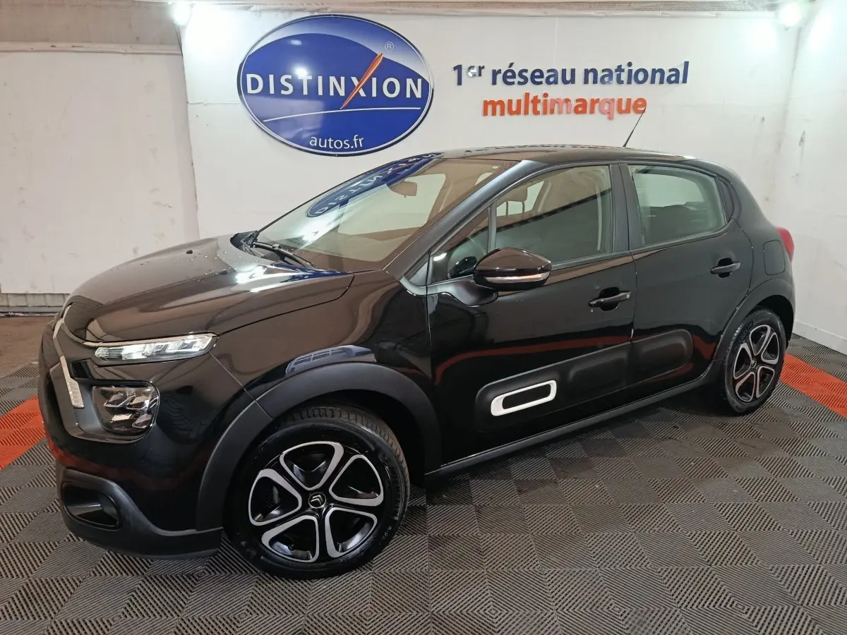 Citroën C3 BlueHDi 100 BVM PLUS noire vue 3/4 avant droit avec jantes spécifiques et protections latérales blanches.