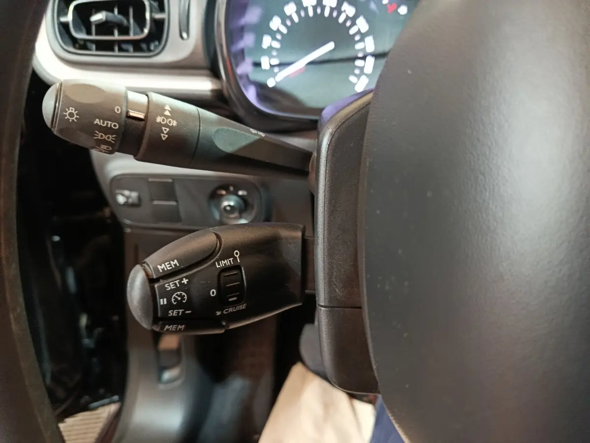 Gros plan sur le volant noir de la Citroën C3 2024 avec commandes de régulateur et commodo d’éclairage.