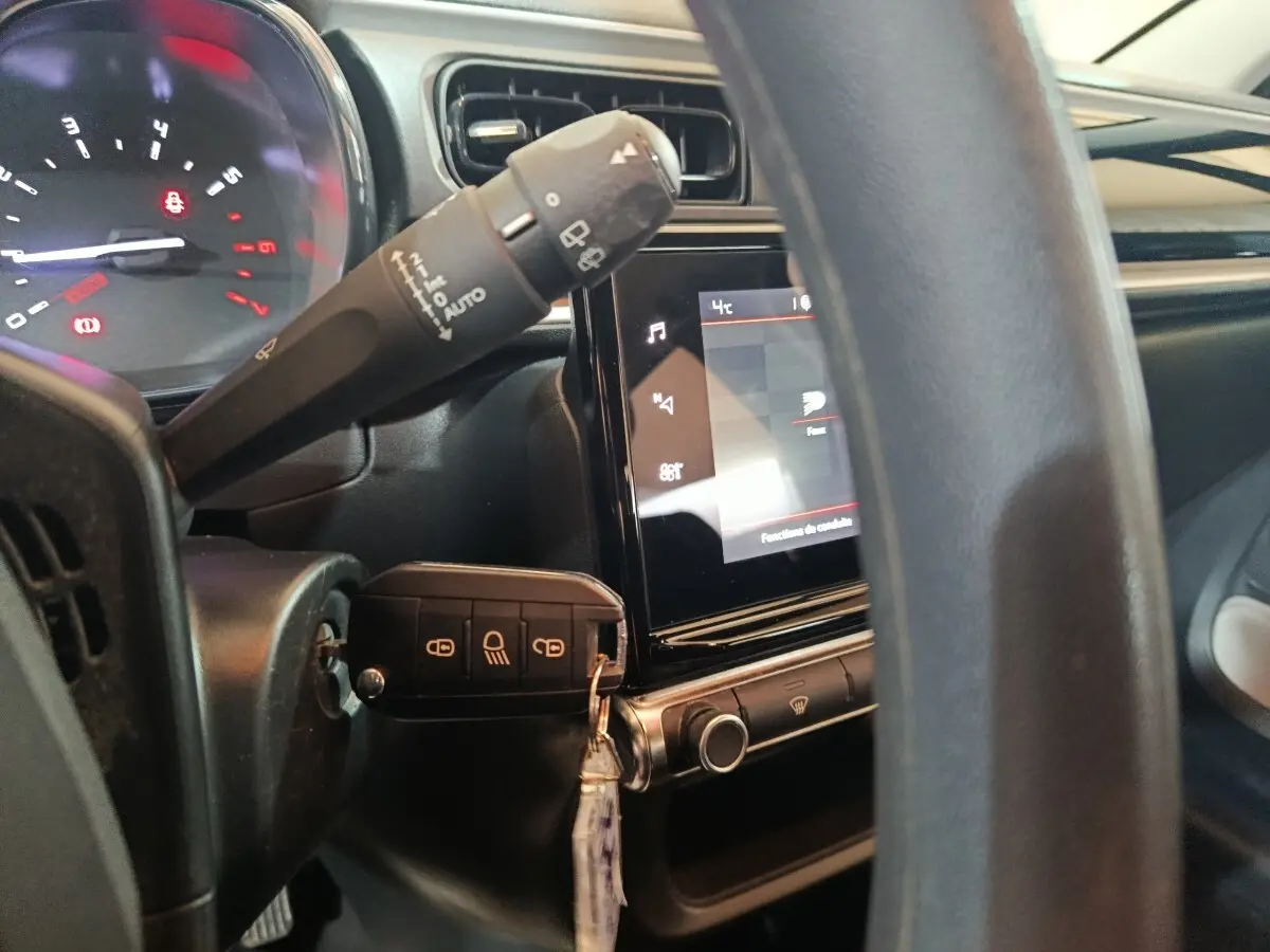 Vue rapprochée du tableau de bord et volant noir de la Citroën C3 2024 avec écran tactile et clé insérée.