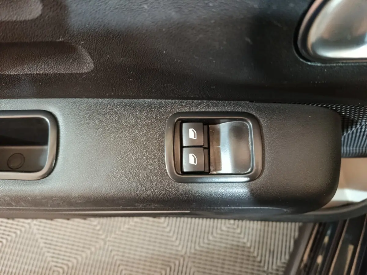 Gros plan sur les commandes des vitres électriques côté conducteur de la Citroën C3 noire 2024.