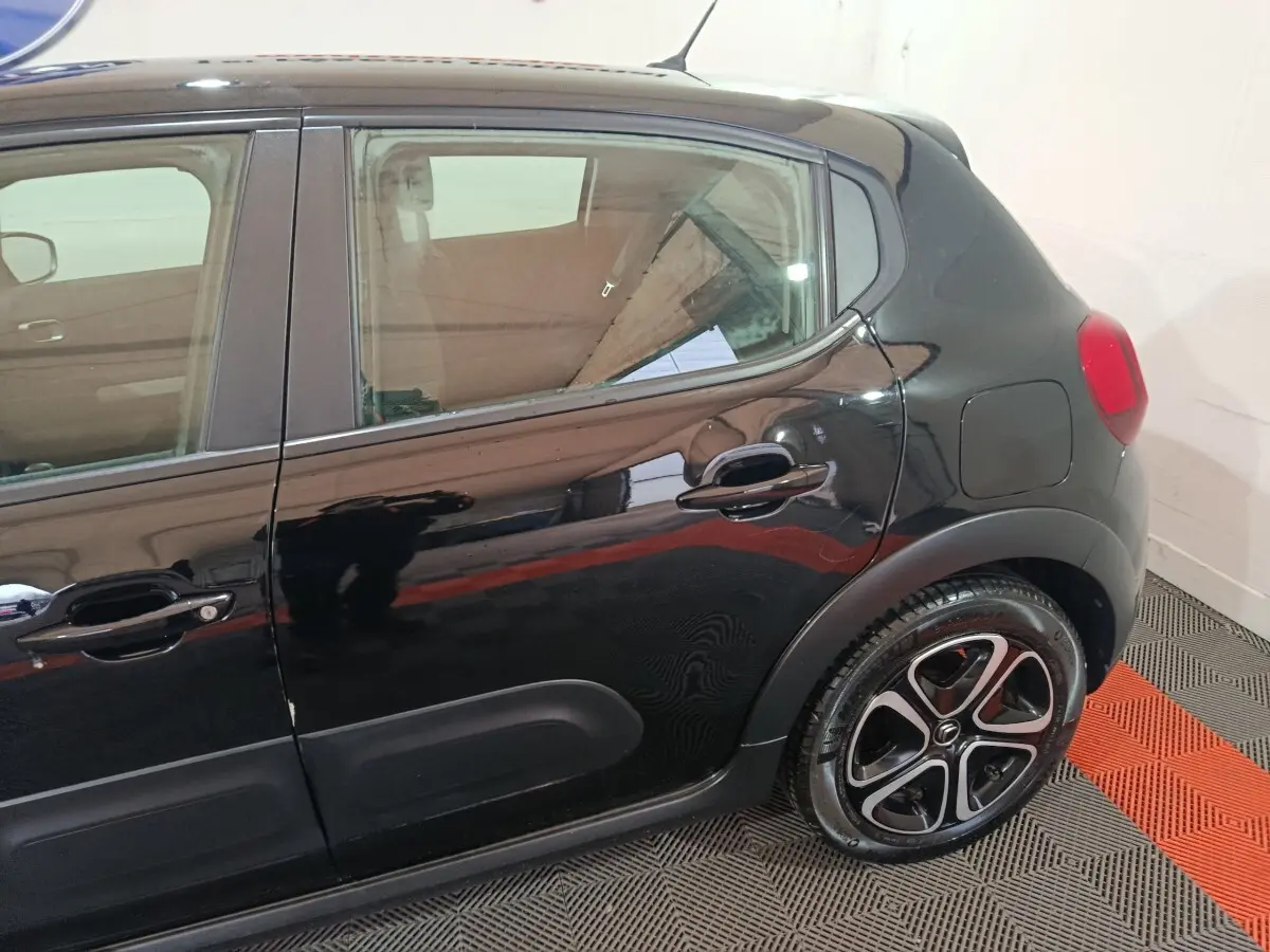 Vue latérale côté droit de la Citroën C3 noire 2024, mettant en valeur la porte arrière et la roue au design distinctif.
