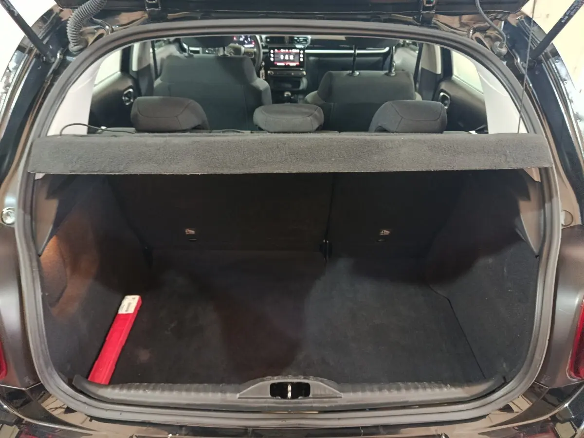 Vue arrière du coffre ouvert d'une Citroën C3 noire 2024, montrant l'intérieur spacieux et la tablette cache-bagages.