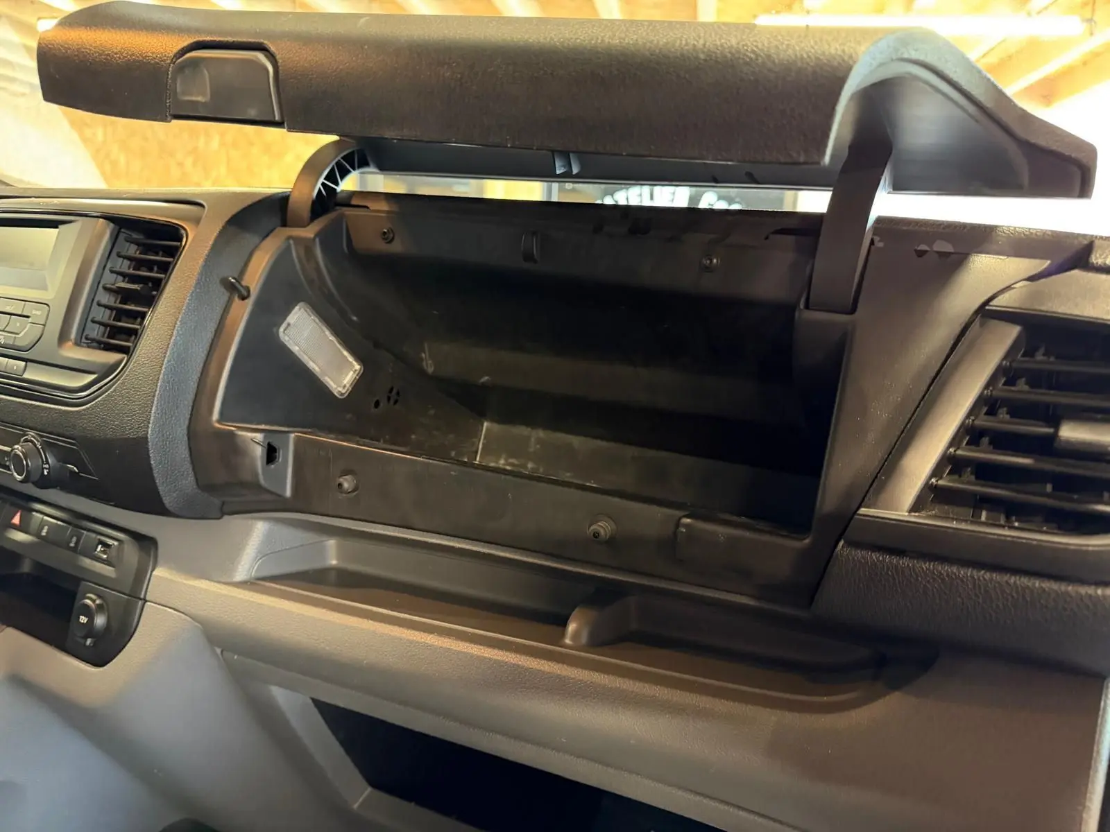 Intérieur du Citroën Jumpy 2.0 BlueHDi 180 2022, vue sur la boîte à gants ouverte et tableau de bord gris.