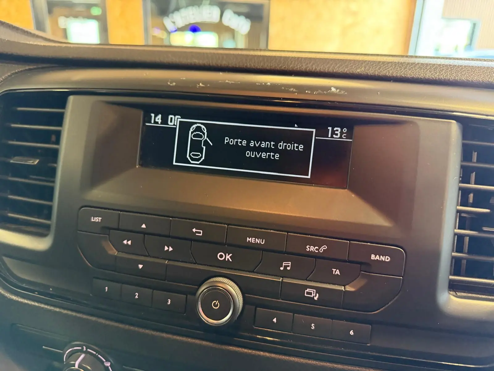 Vue rapprochée de l’écran central du tableau de bord du Citroën Jumpy gris affichant l’alerte porte avant droite ouverte.