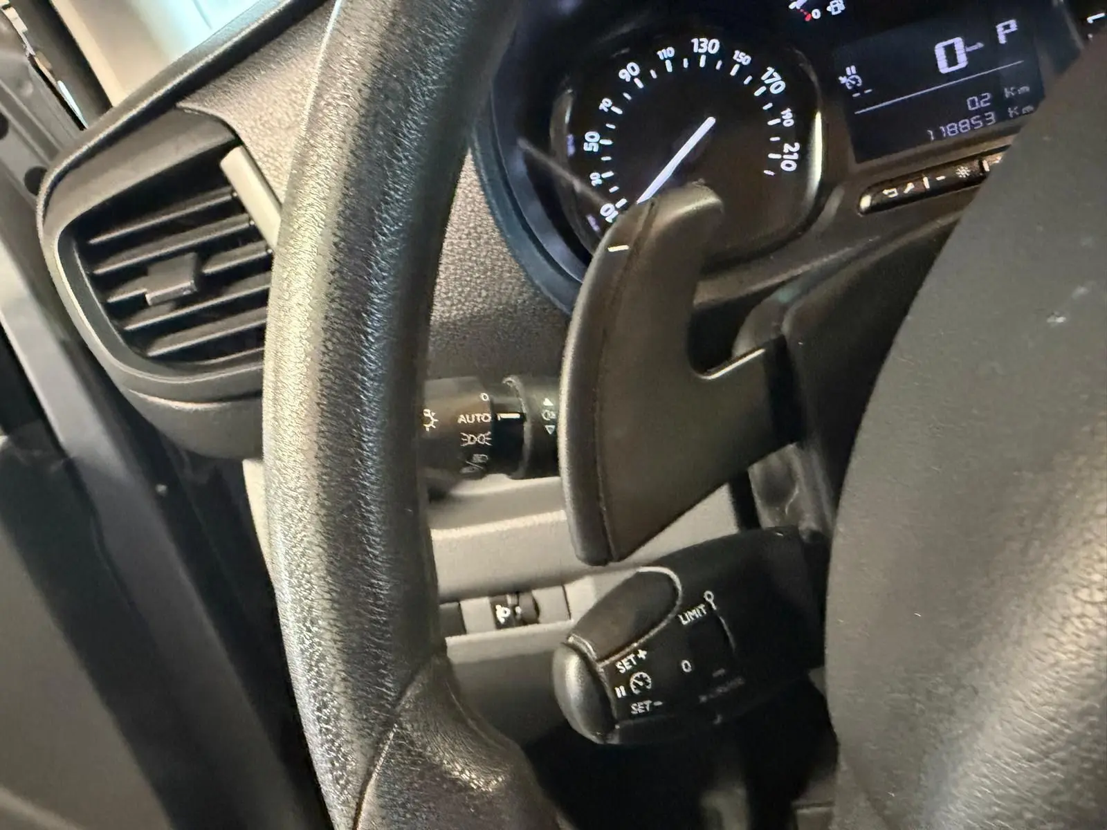 Gros plan sur le volant et le tableau de bord du Citroën Jumpy gris, montrant la commande de régulateur de vitesse et le compteur.