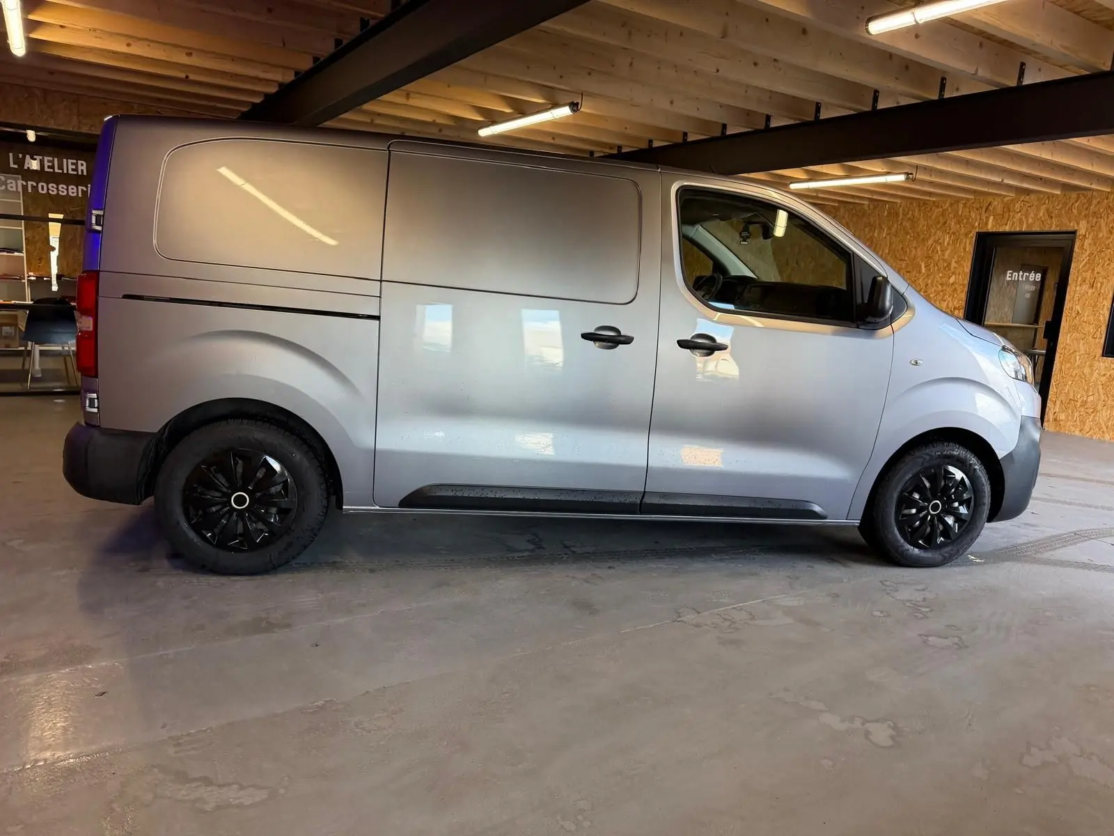 Vue de profil côté droit d’un Citroën Jumpy gris métallisé 2022 avec portes latérales et jantes noires.