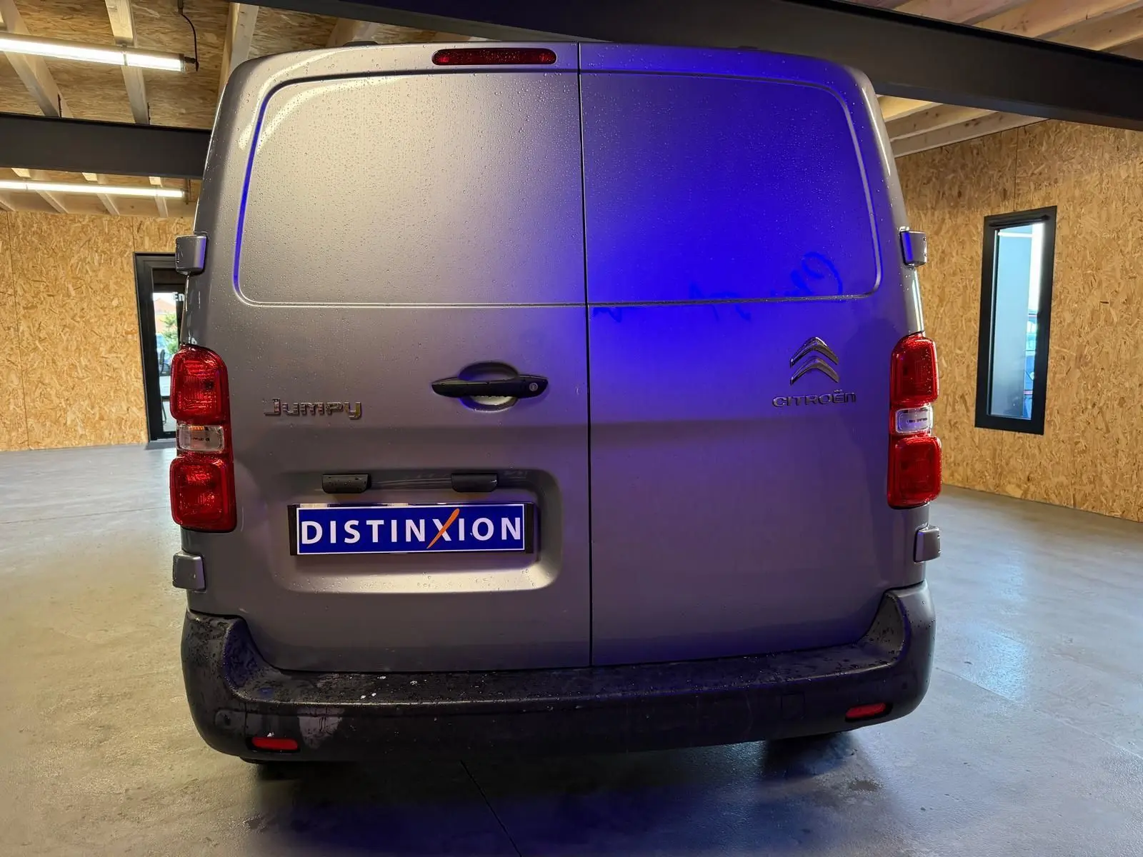 Vue arrière d'un Citroën Jumpy gris métallisé 2022 avec portes battantes et plaque Distinxion en intérieur.