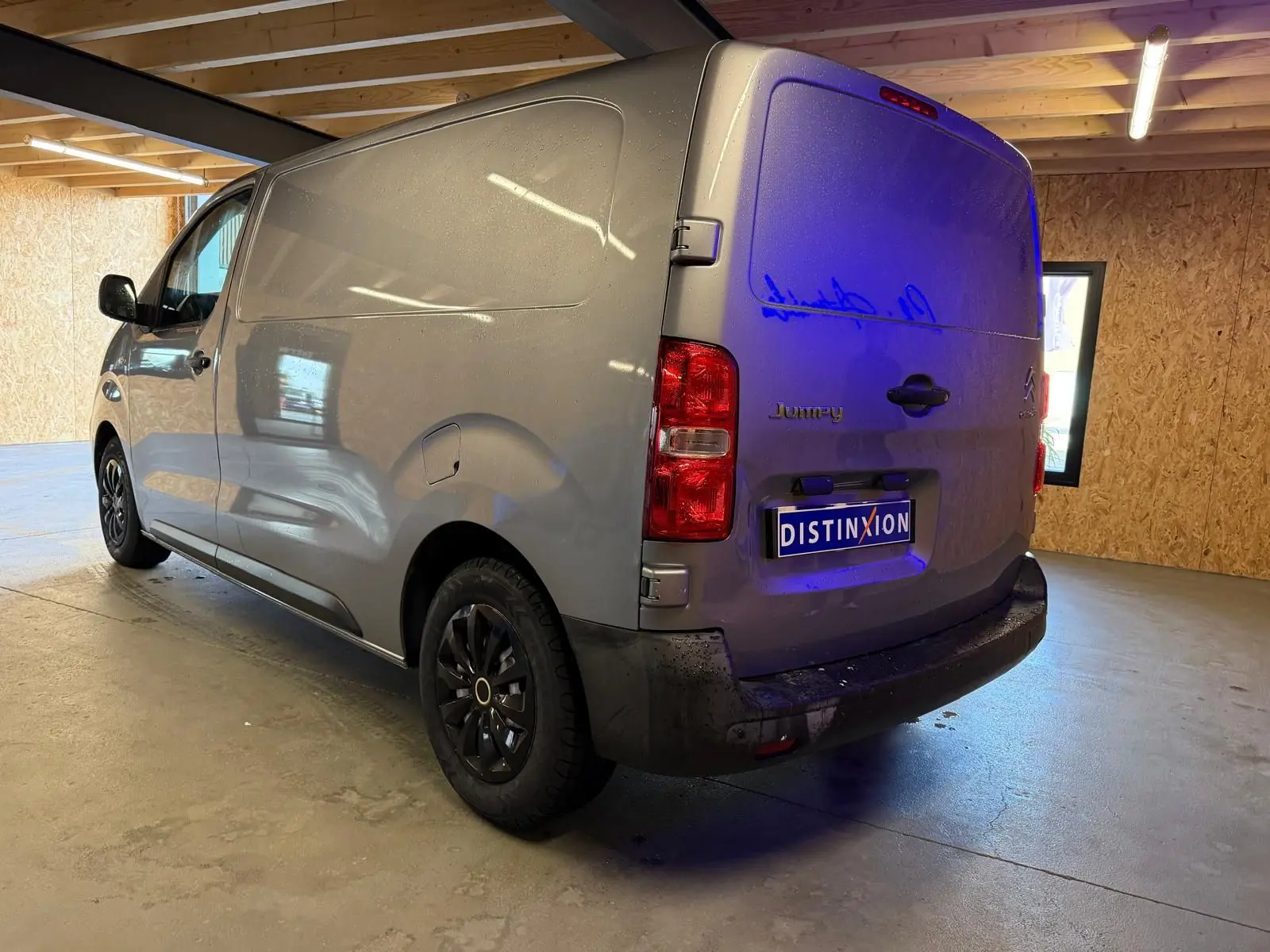 Vue 3/4 arrière droite d'un Citroën Jumpy gris métallisé 2022 avec portes battantes et jantes noires en intérieur.