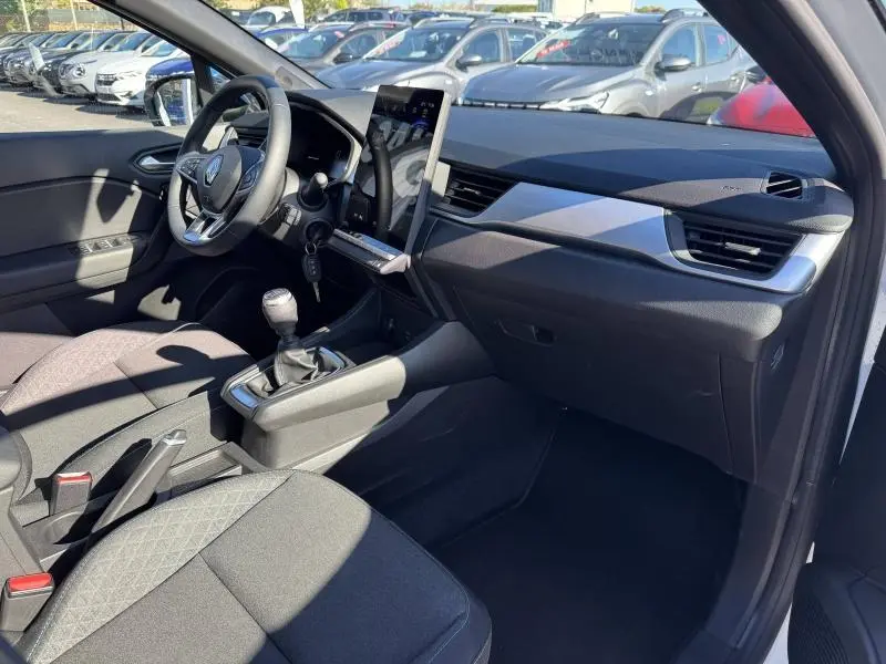 Vue intérieure côté conducteur du Renault Captur 2025, montrant la console centrale avec boîte manuelle et tableau de bord moderne.
