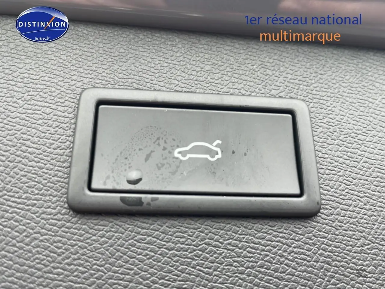 Bouton d'ouverture du coffre en plastique noir sur tableau de bord texturé d'un CUPRA Formentor gris graphene.