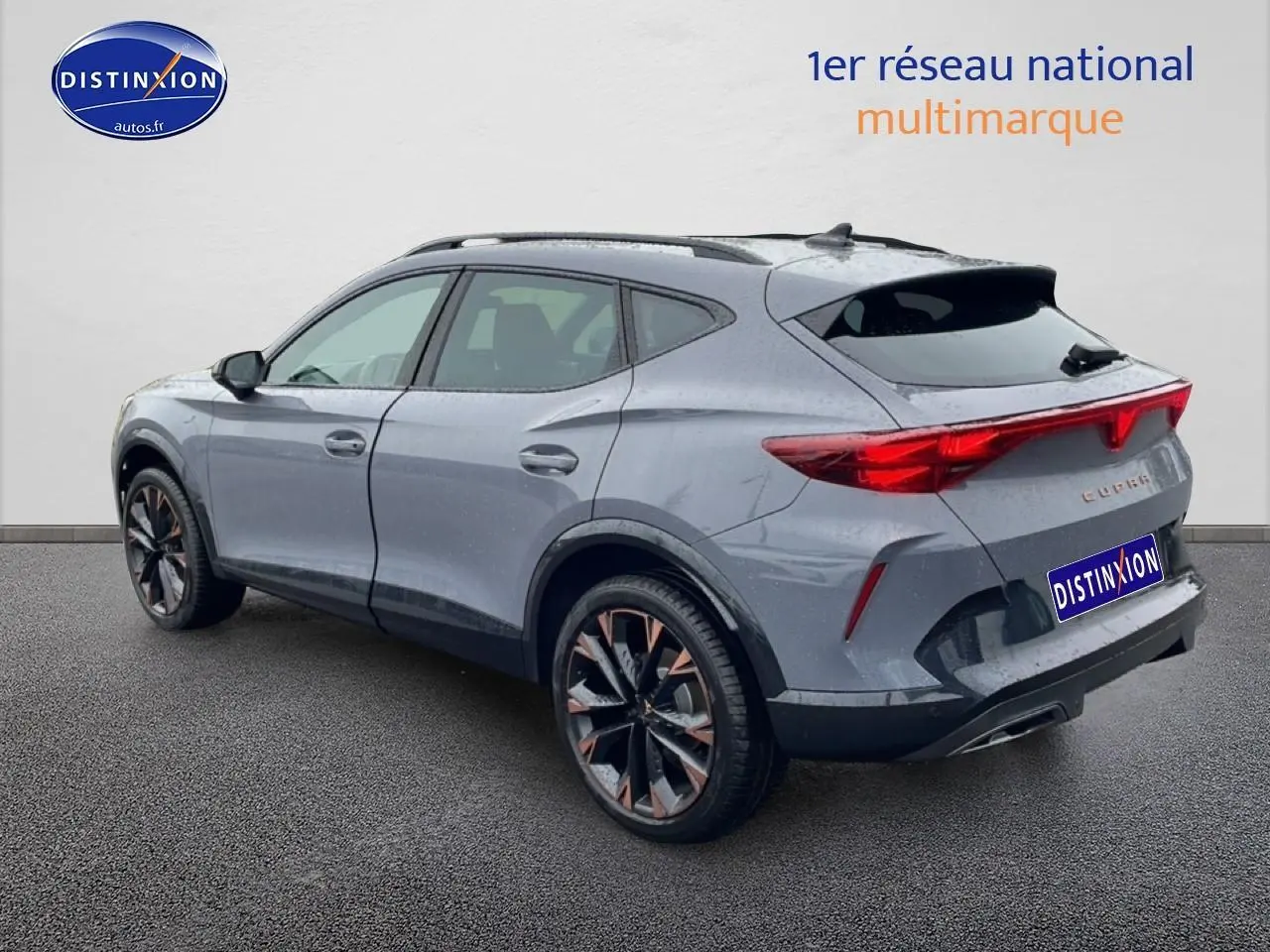 Vue 3/4 arrière droite d’un CUPRA Formentor gris graphene avec jantes noires et bronze, feux arrière LED allumés.