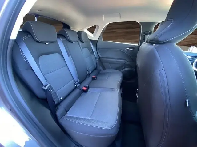 Vue intérieure arrière du Renault Captur gris clair 2023 montrant la banquette 3 places avec ceintures et appuie-têtes.
